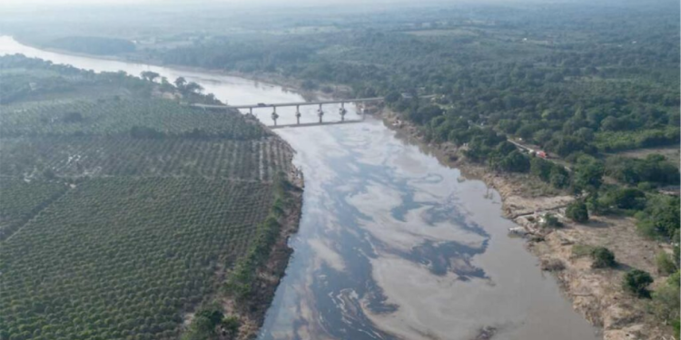 Derrame de petróleo en río - PUNTO DE ENCUENTRO Una vista aérea de un río donde se distinguen patrones oscuros y aceitosos sobre la superficie del agua, indicando la presencia de un derrame-de-petróleo.