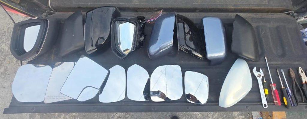 robo de autopartes - PUNTO DE ENCUENTRO aRow of car side mirror glass and housings laid out on a black mat with basic tools nearby.