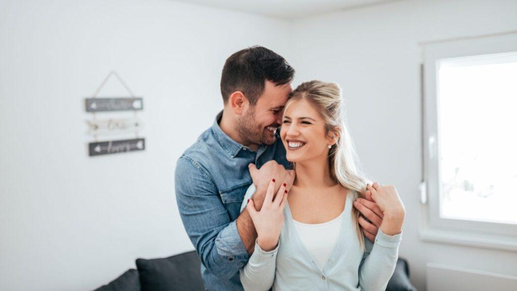 Pareja abrazandose con alegría dentro de un departamento con buena iluminación